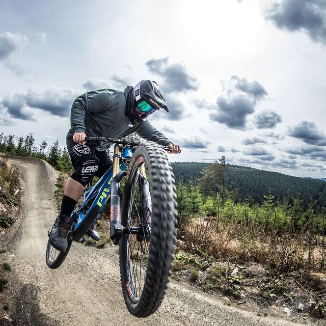 Biker in rasanter Abfahrt auf dem Flowtrail im MTB Zone Bikepark Willingen unter wolkenverhangenem Himmel