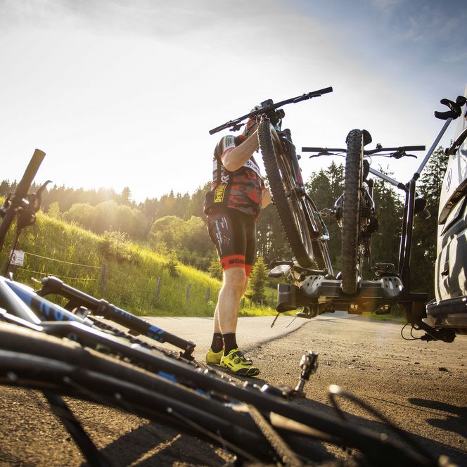 Ein Mann verstaut die Mountainbikes auf dem Fahrradanhänger seines Autos