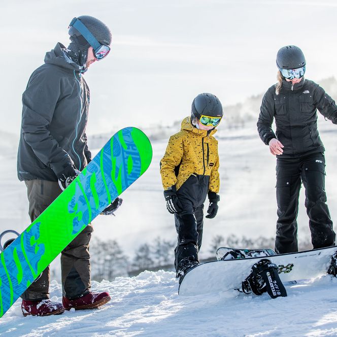 Familie mit Snowboards auf der Skipiste in Willingen