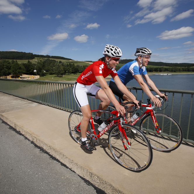 2 Rennradfahrer fahren über eine Brücke am Diemelsee