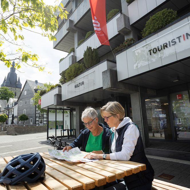 2 Bikerinnen sitzen am Marktplatz in Brilon und schauen auf eine Landkarte