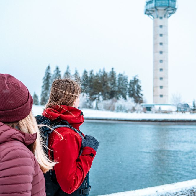 2 Frauen wandern im Winter am Bergsee auf dem Ettelsberg, im Hintergrund der Hochheideturm